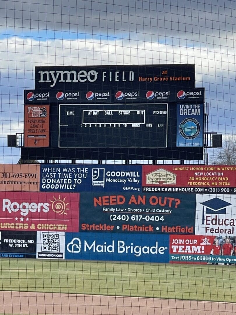 a Baseball Stadium Scoreboard at Nymeo Field Displays Pepsi Logos and is Blank Showing No Scores or Stats Colorful Advertisements for Local Businesses and the Frederick Keys Schedule Cover the Lower Part of the Scoreboard with Netting in Front