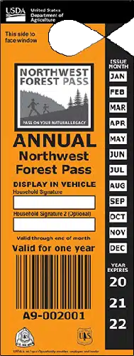 An orange annual Northwest Forest Pass from the USDA, perfect for Bend hikes or hikes near Bend Oregon, with months listed vertically on the right, display instructions, a space for signature, and barcodes, serial number, and logos at the bottom. Valid for one year.