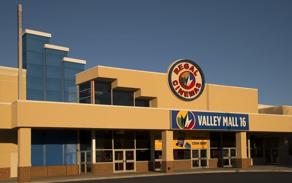 a Beige and Blue Frederick Movie Theatre This Regal Cinemas Building Features Large Glass Panels Prominent Regal Cinemas and Valley Mall 16 Signs Above the Entrance with Several Double Glass Doors Below Under a Clear Blue Sky