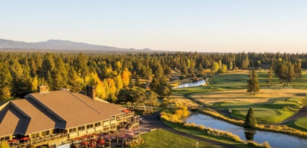 the Sunriver Lodge at Sunriver Resort with Its Golf Course is Surrounded by Lush Green Fairways and Autumn Colored Treesa Picturesque Choice for Those Seeking Where to Stay in Bend Oregon with Mountain Views Under a Golden Sunset Sky