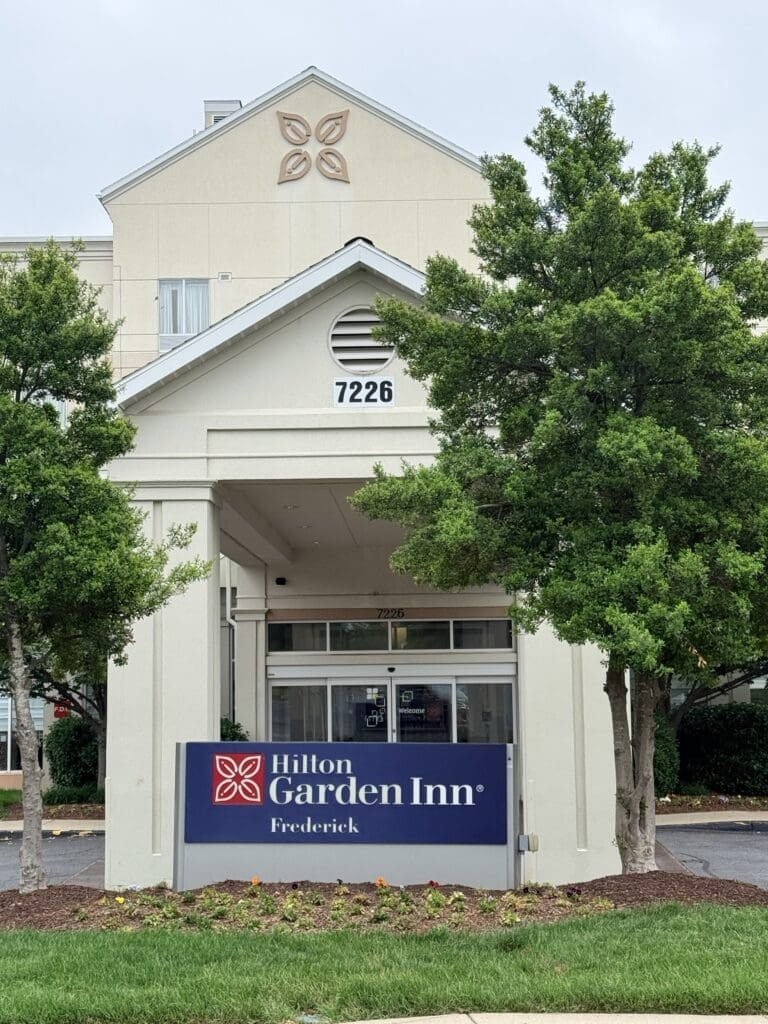 Hotel Entrance of Hilton Garden Inn with Address 7226 Surrounded by Green Trees
