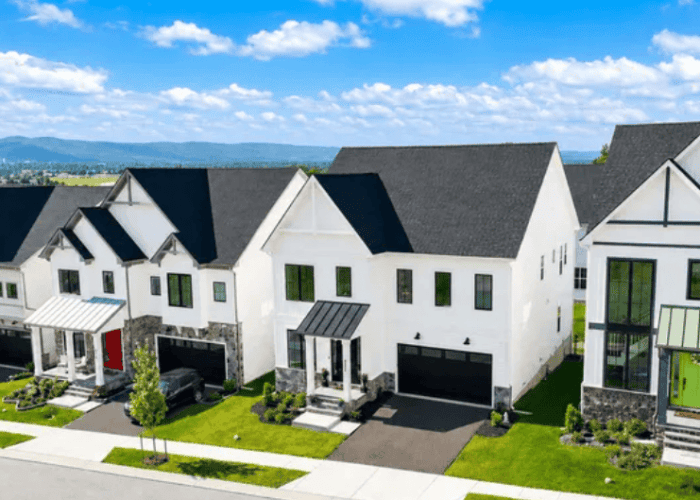 Row of modern white townhouses with attached garages on a sunny street.