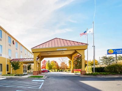 Comfort Inn entrance with a yellow canopy, flagpoles and waving American flag against a blue sky