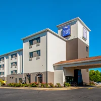 Sleep Inn hotel exterior under a clear blue sky, with a driveway and landscaped plants in front.